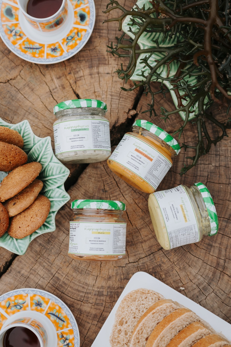 Potes de patê e geleia Kappaphycus sobre tábua de madeira, com torradas, café e biscoitos